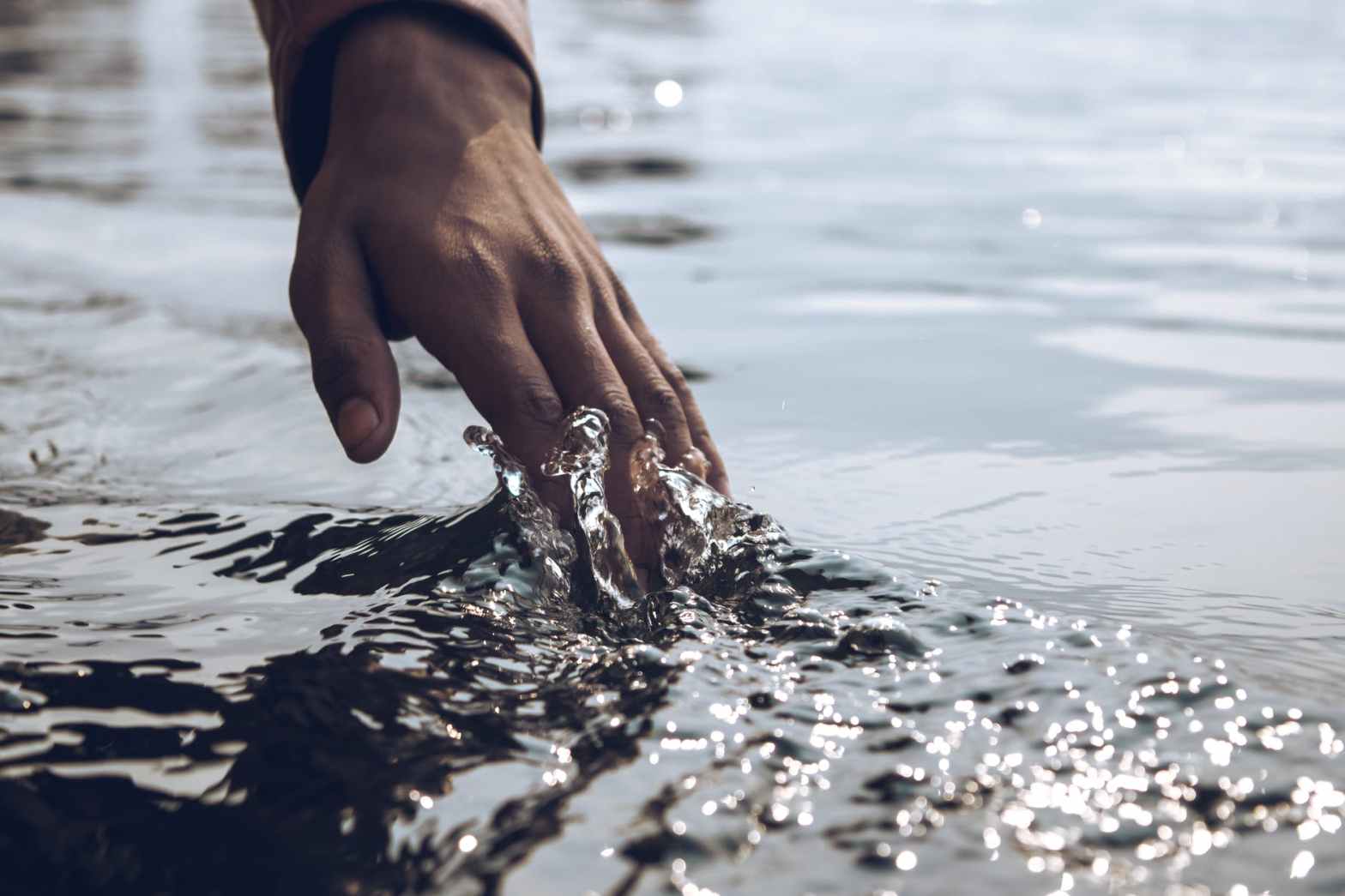 close up photo of a person s hand touching body of water