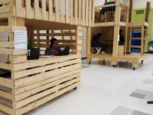Middle school students study on laptops inside a treehouse inside a school cafeteria