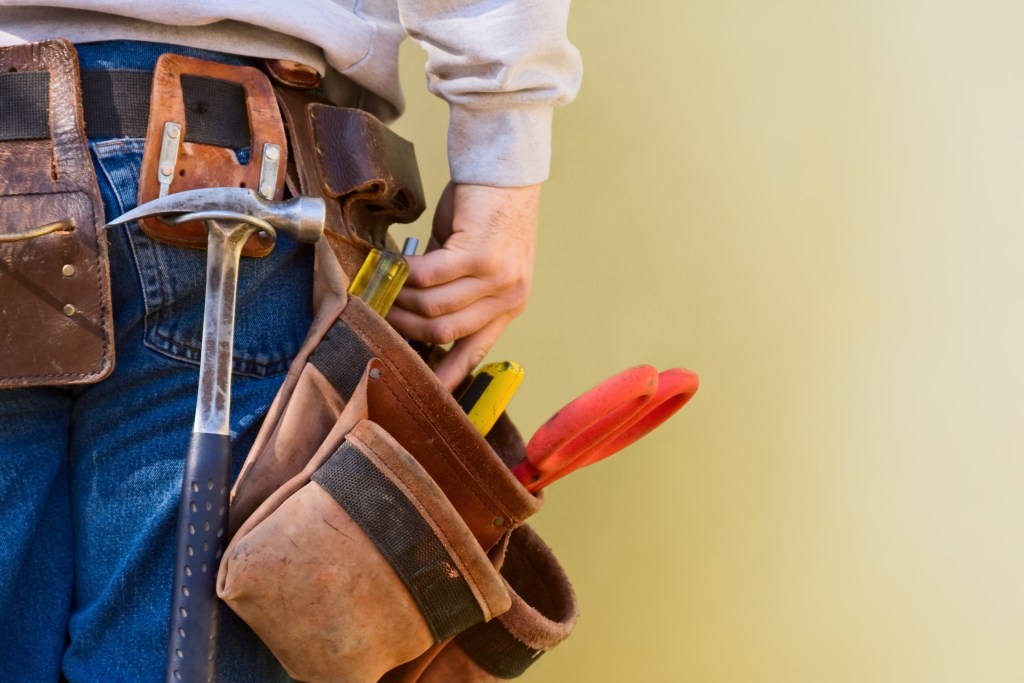 Young Construction Worker Reaches Into His Tool Belt