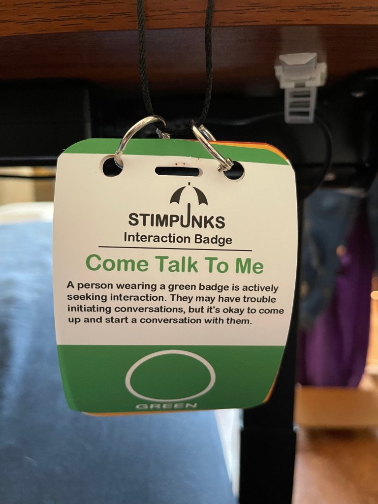 Green interaction badge hanging from two binder rings and a black neck cord