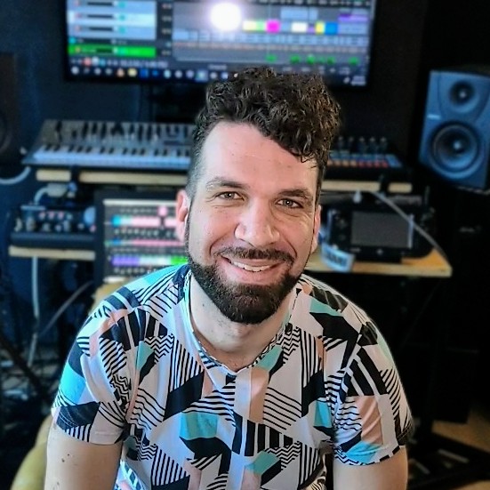 En person som sitter framför poddutrustning ler mot kameran