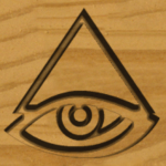 an eyeball underneath a cone etched in wood