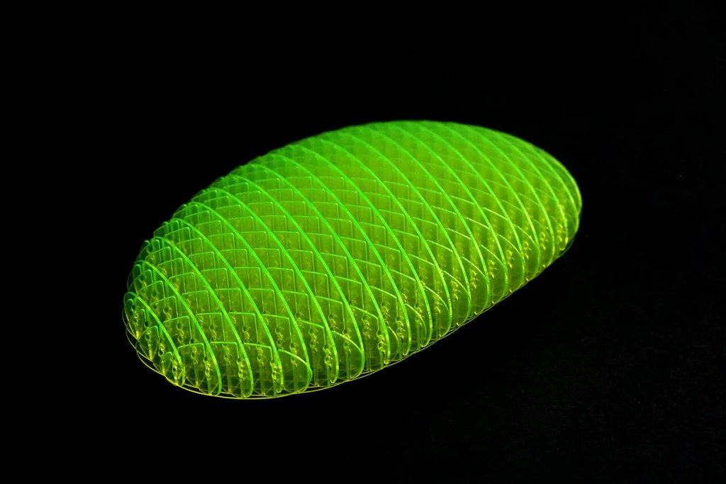 A fidget toy made from a lattice of day glow green plastic, resembling a flat, oblong worm