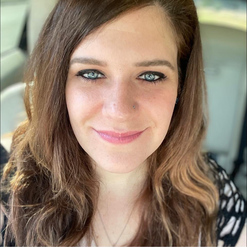 אישה לבנה עם שיער חום מחייכת למצלמה