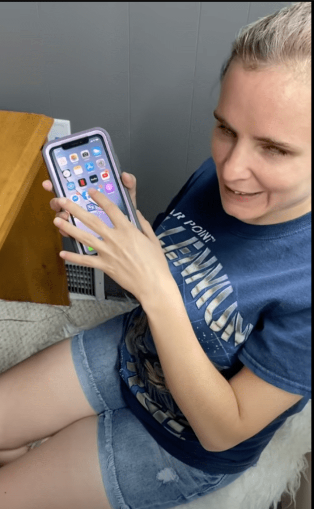 A white woman holds and taps a phone