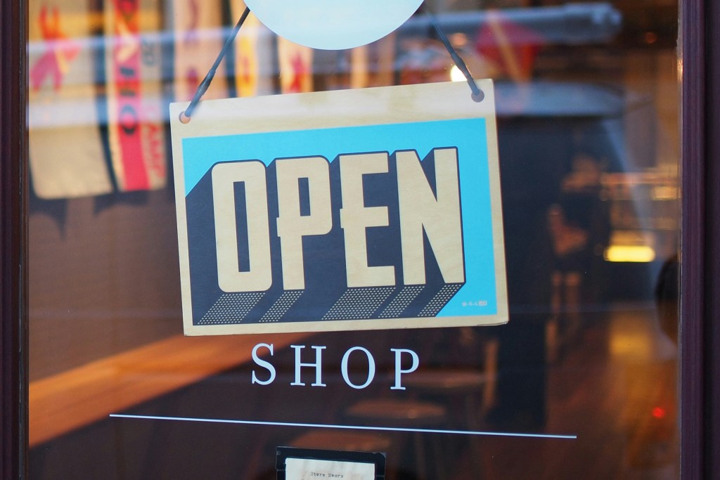 A glass shop door with a sign saying 'open'.