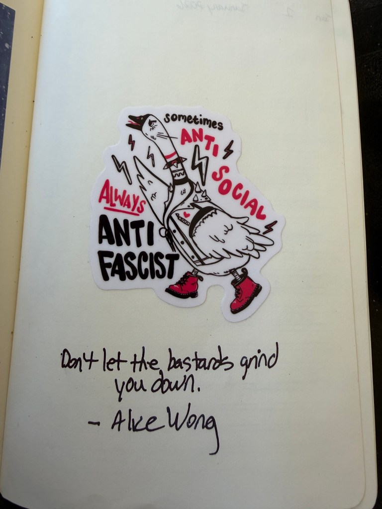 Sticker of an illustration of an angry goose wearing a punk battle jacket and Doc Marten boots with a wing raised in the air. Text reads: Sometimes anti-social, always anti-fascist”

Below the sticker is hard written text in dark fountain pen ink that reads:

Don’t let the bastards grind you down. —Alice Wong