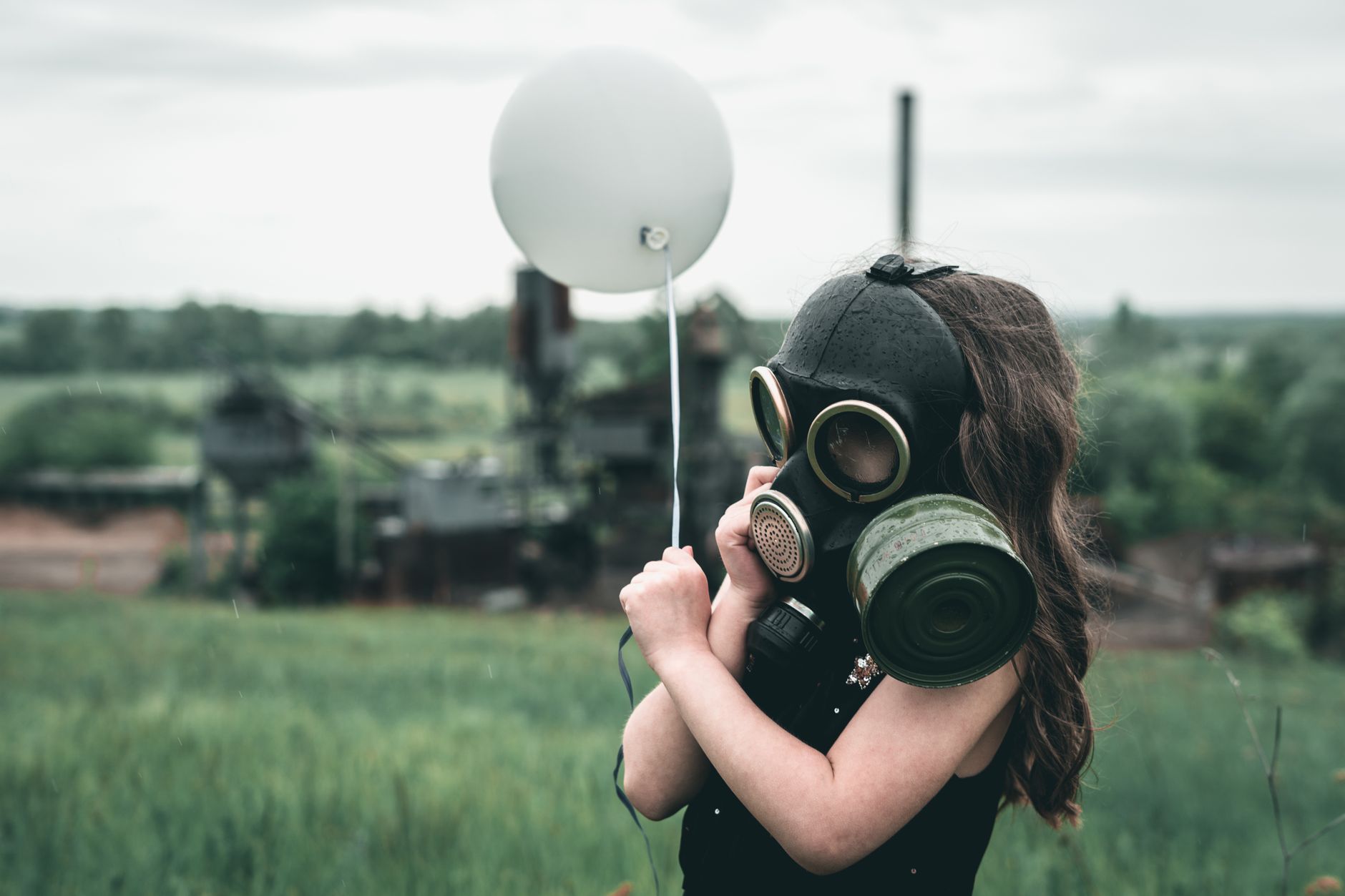 young girl holding a balloon while wearing gas mask
