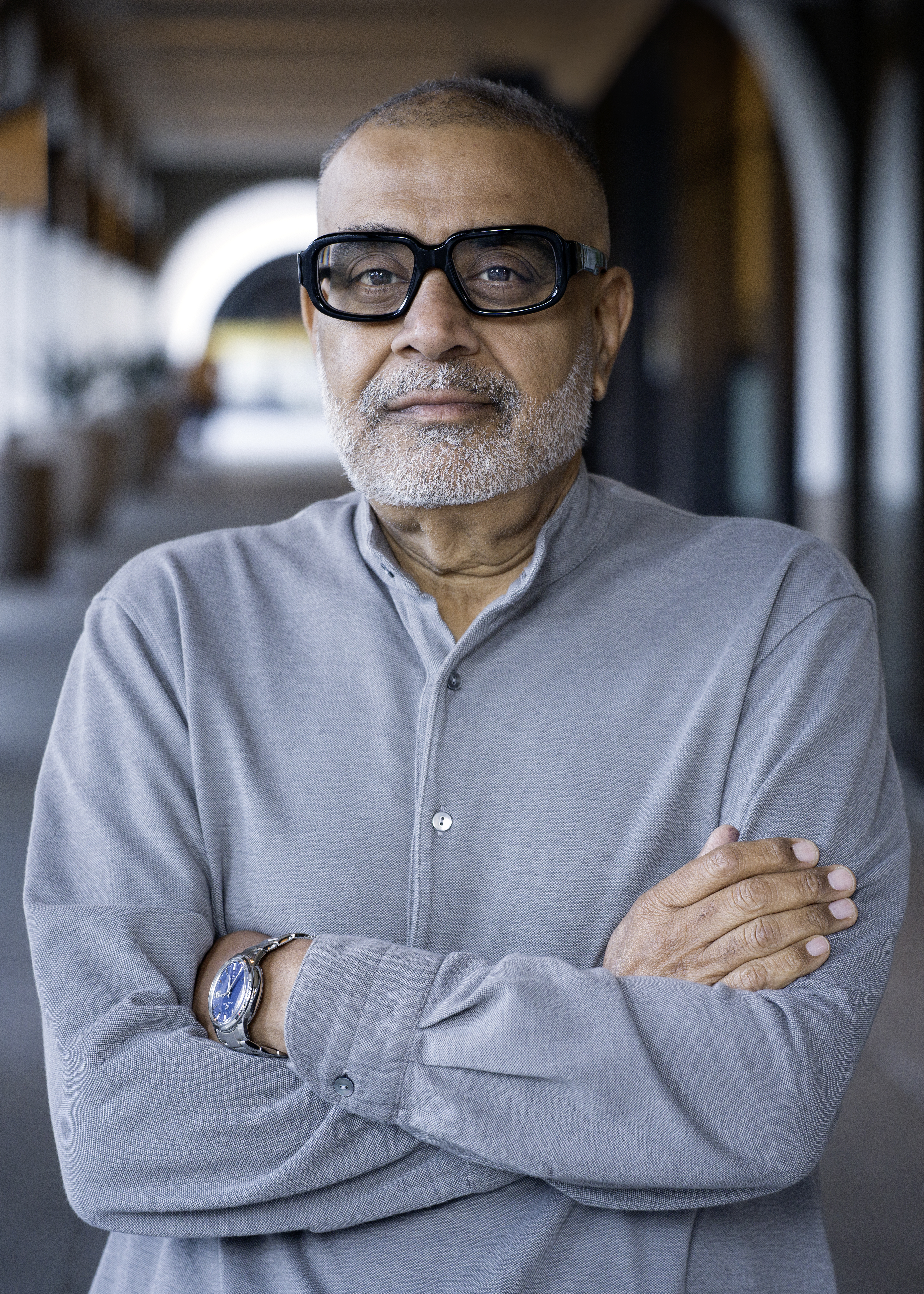 Portrait of a brown-skinned man with grey hair and glasses with thick, black frames.