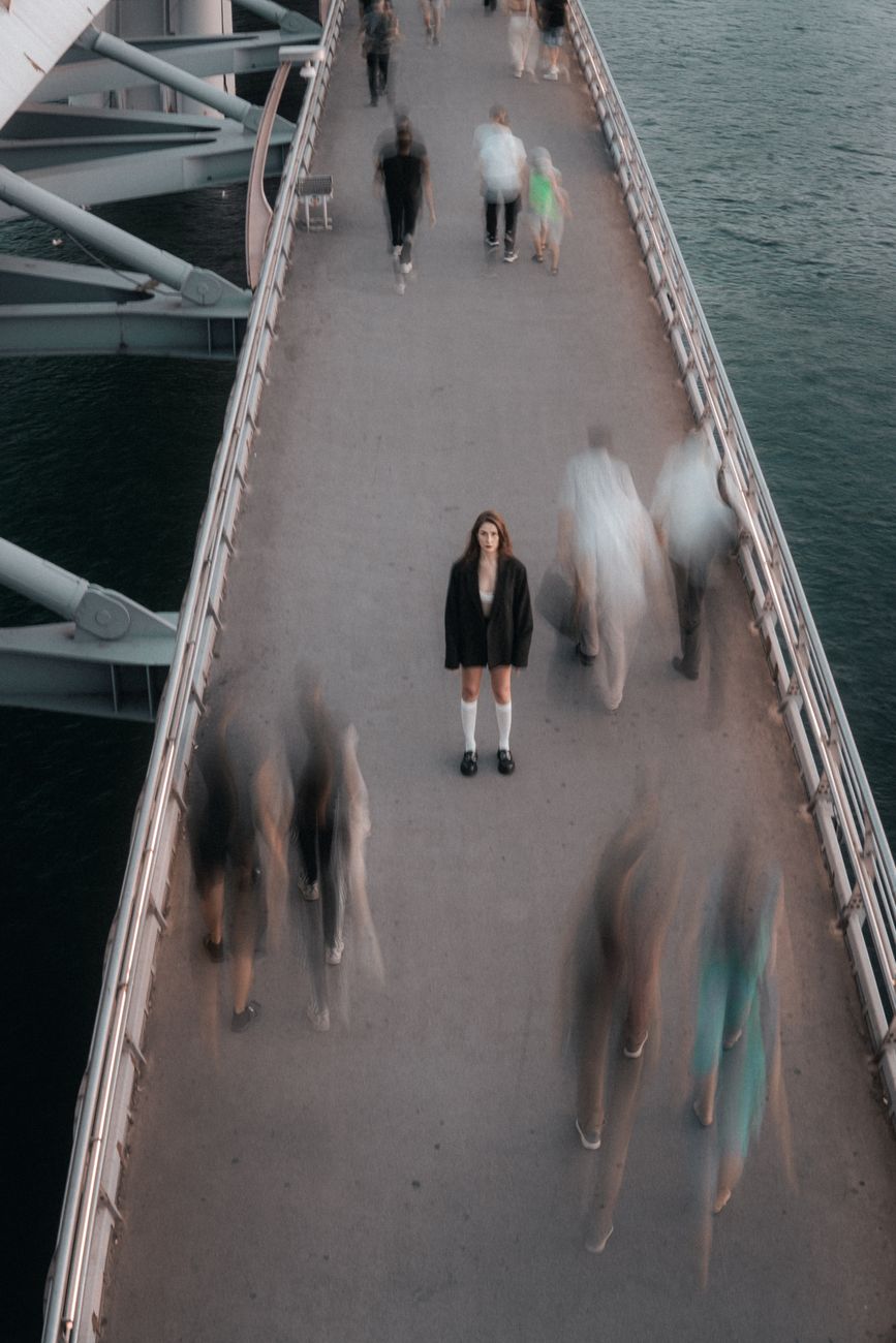 people walking around woman in coat standing on halic bridge in istanbul